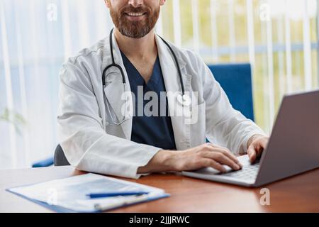 Nahaufnahme eines Mitarbeiters im Gesundheitswesen mit Stethoskop, der ein Notebook verwendet, während er in der Arztpraxis arbeitet Stockfoto