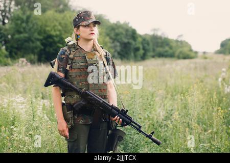 Ukrainische Militärangehörende mit einem Maschinengewehr in den Händen in der Mitte eines Feldes Stockfoto