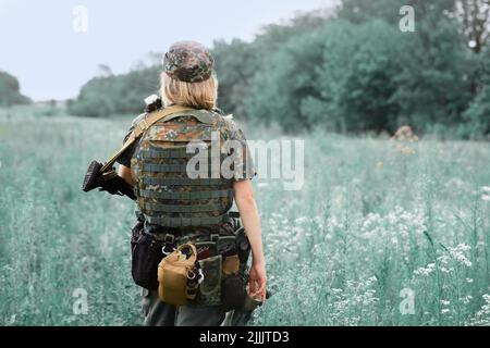 Ukrainische Militärangehörende mit einem Maschinengewehr in den Händen in der Mitte eines Feldes Stockfoto