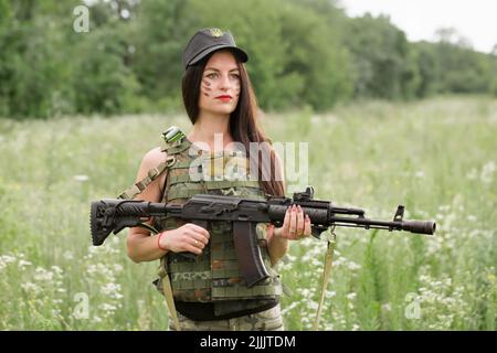 Ukrainische Militärangehörende mit einem Maschinengewehr in den Händen in der Mitte eines Feldes Stockfoto