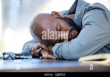 Wir alle brauchen eine Pause. Ein junger Geschäftsmann, der bei der Arbeit in einem Büro schläft. Stockfoto