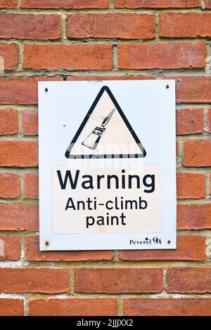 Ein Warnschild über Anti-Climb-Farbe mit einer klassischen, ikonischen Zeichnung eines Standard-Pinsels. In einem Backsteinhaus in Cardiff, Wales, United Stockfoto