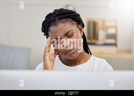 Kann dieser Tag schon enden. Eine junge Geschäftsfrau, die am Arbeitsplatz unter Kopfschmerzen leidet. Stockfoto