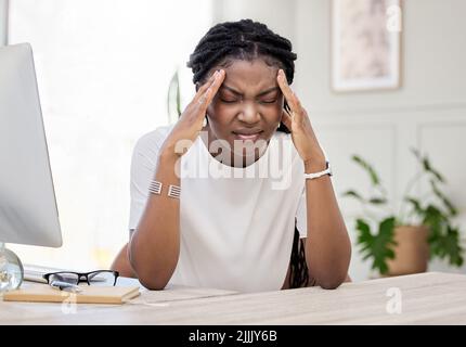Eine junge Geschäftsfrau, die an Kopfschmerzen bei der Arbeit leidet. Stockfoto
