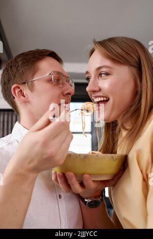 Lächelnd liebevoller Ehemann füttert Frau, junges Paar genießen zarten Moment, romantische Datum, Spaß haben, japanische Küche essen, glückliche Familienausgaben Stockfoto