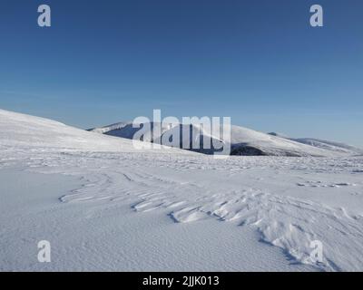 Blick auf Carn Na Criche, mit Braeriach links und Cairn Toul rechts. Aufgenommen auf dem gefrorenen Hang zwischen Sgor Gaoith & Carn Ban Mor. Stockfoto