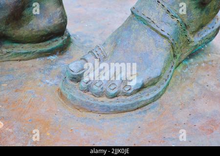 Nahaufnahme, Detail eines bescheidenen Sandelschuhs auf der Bronzestatue des indischen Unabhängigkeitsführers Mahatma Gandhi. In Cardiff, Wales, Vereinigtes Königreich. Stockfoto