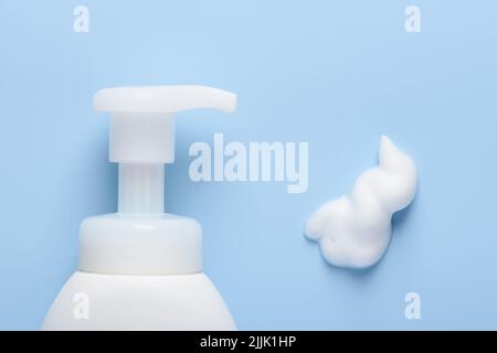 Weiße Kosmetikflasche mit Pumpspender und Schaumstoffabstrich auf blauem Hintergrund Draufsicht flach liegend Stockfoto