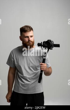 Professioneller Videofilmer, der mit Steadicam gute Aufnahmen macht. Der Kameramann, der einen Stabilisator in der Hand hat, nimmt ein Video auf dem slr-Video auf Stockfoto