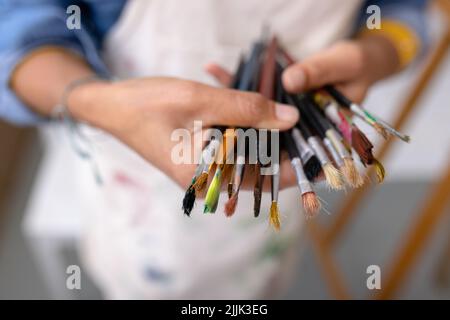 Bild der Hände der Biracial Künstlerin mit Pinsel im Studio Stockfoto