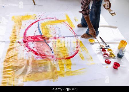 Bild der Hände von Biracial Künstlerin Malerei auf dem Boden im Studio Stockfoto