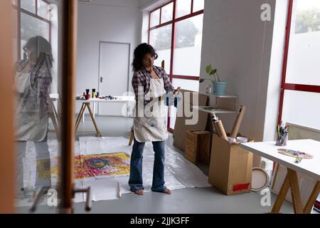 Bild einer biracial Künstlerin in Schürze Reinigung Hände im Studio Stockfoto