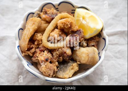 Spanische Meeresfrüchte, knusprig frittierte Babykraken, Fisch, Calamari-Ringe mit Zitrone serviert, Nahaufnahme Stockfoto