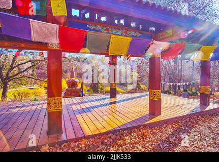 Der sonnige Herbstmittag im Tibetischen Garten mit buddhistischen Fahnen, Pavillon für Meditation und Chörten im Hintergrund, Kyiv Botanischer Garten, Ukraine Stockfoto