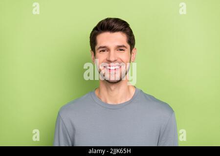 Foto von kühlen Millennial Brunet Kerl tragen graues Hemd isoliert auf grünem Hintergrund Stockfoto