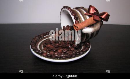 Eine kunstvolle handgemachte Kaffeebohnen, die aus einer Tasse verschüttet werden Stockfoto