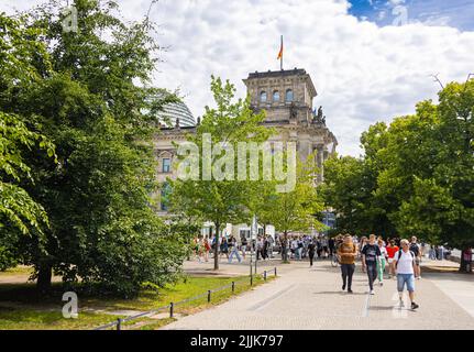 Berlin, Deutschland - 29. Juni 2022: Das Reichstagsgebäude, Sitz des deutschen bundestages. Die deutsche Flagge auf einem Fahnenmast. Touristen gehen zu Fuß Stockfoto