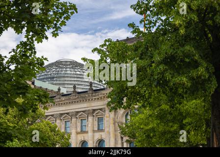 Berlin, Deutschland - 29. Juni 2022: Die Kuppel des Reichstags, Sitz des Deutschen Bundestages, durch die Bäume des Tiergartens. Die Kuppel ist zu einem m geworden Stockfoto