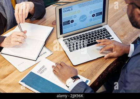 Nahaufnahme eines afrikanischen Geschäftsmannes mit Laptop, Geschäftsbericht auf dem Bildschirm und Besprechung der Pläne mit dem Partner bei der Besprechung Stockfoto