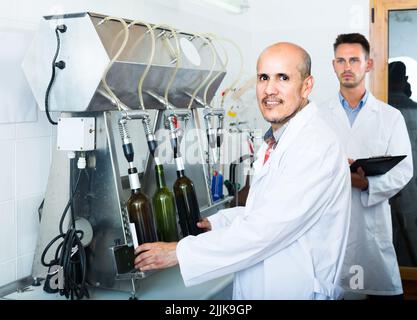 Porträt eines männlichen Weinarbeiters mit Abfüllmaschinen in der Fabrik Stockfoto