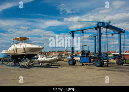 Ein fahrbarer Hängeschiff oder Hebezeug und ein kleines Freizeitboot, das auf einer Bootskradle am Yachthafen von Izola an der slowenischen Adriaküste repariert wird Stockfoto