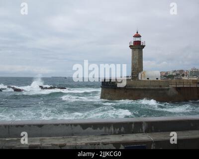 Foz do Douro Leuchtturm neben einem Gewässer und einem hellen bewölkten Himmel im Hintergrund Stockfoto