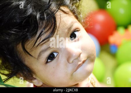 Ein Porträt eines niedlichen kleinen indischen Babys mit großen Augen auf dem Spielplatz Stockfoto