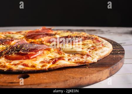 Eine köstliche spanische iberische Schinkenpizza auf einem Holztisch Stockfoto