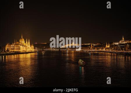 Panoramablick auf das Parlamentsgebäude und die Donau in Budapest, Ungarn. Parlament und Überlegungen . Abendbeleuchtung des Gebäudes. Stockfoto