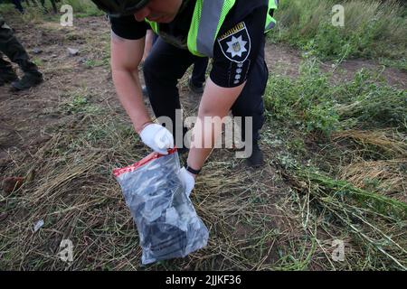 CHARKIW, UKRAINE - 26. JULI 2022 - Ein Polizeibeamter sammelt die Fragmente am Tatort nach einem morgendlichen Angriff der russischen Besatzer auf die zentrale KH Stockfoto