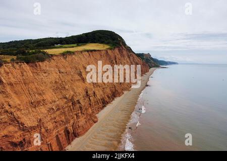 Sidmouth, Devon, Großbritannien. 27.. Juli 2022. Wetter in Großbritannien. Blick aus der Luft auf die bröckelnden roten Sandsteinklippen im Badeort Sidmouth in Devon an einem Tag mit heißer, trübiger Sonne. Bildnachweis: Graham Hunt/Alamy Live News Stockfoto