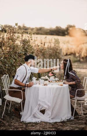 Eine vertikale Aufnahme eines kaukasischen Paares, das in einem wunderschönen Weinberg zu Mittag gegessen hat Stockfoto