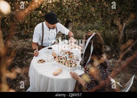 Ein wunderschönes kaukasisches Paar, das in einem Weinberg zu Mittag gegessen hat Stockfoto