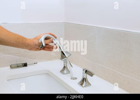 Ein Klempner montiert einen Wasserhahn für das Badezimmer und installiert Stockfoto