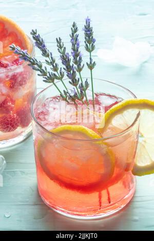 Sommercocktail oder Mocktail, kaltes Getränk mit Zitrone und Lavendel, Party-Limonade mit Eis auf blauem Hintergrund, Nahaufnahme Stockfoto