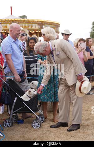 Der Prinz von Wales schürt Dill, einen Jack Russell Terrier, als er während ihres Besuchs und ihrer Tour zur Sandringham Flower Show im Sandringham House in Norfolk Mitglieder der Öffentlichkeit mit der Herzogin von Cornwall trifft. Bilddatum: Mittwoch, 27. Juli 2022. Stockfoto