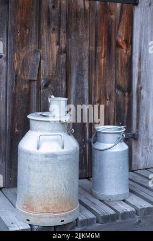 Nahaufnahme von alten Vintage-Aluminium-Milchdosen auf alten Holzbrettern. Stockfoto