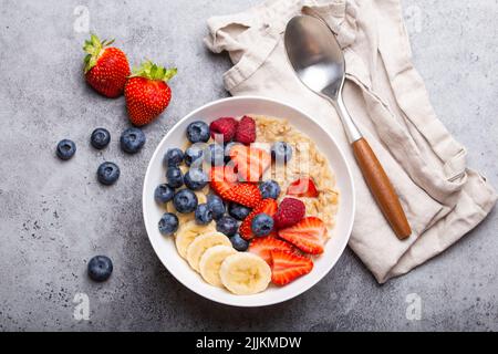 Haferflocken Haferbrei mit Obst und Beeren auf Stein rustikalen Tisch Stockfoto