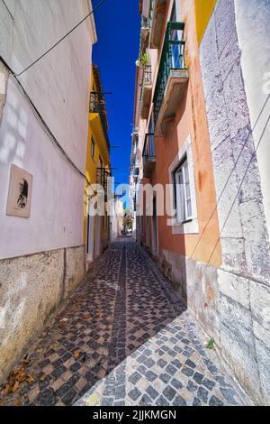 Eine vertikale Aufnahme einer kleinen Gasse durch farbenfrohe Gebäude in Lissabon, Portugal Stockfoto