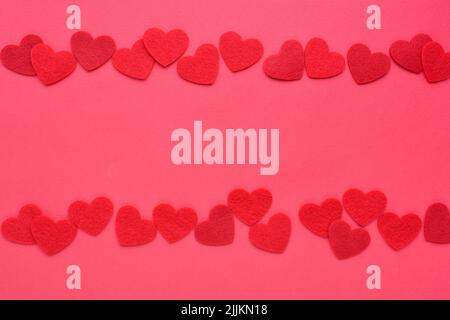 Hintergrund für Ihre Grüße für einen Valentinstag. Filzherzen auf rotem Papier. Stockfoto