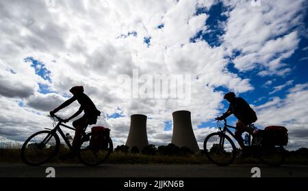 27. Juli 2022, Niedersachsen, Emmerthal: Radler fahren auf dem Weser-Radweg vorbei am stillgelegten Kernkraftwerk Grohnde. Der Verein TÜV glaubt, dass es möglich ist, dass die drei Atomkraftwerke, die Ende letzten Jahres stillgelegt wurden, schnell wieder in Betrieb genommen werden. Nach 36 Jahren wurde das Kernkraftwerk im Weserbergland bei Hamelin am 31. Dezember 2021 vom Netz genommen. Das niedersächsische Umweltministerium geht derweil davon aus, dass die Genehmigung für den Rückbau des Kernkraftwerks Grohnde bis Ende 2022 erteilt wird. Foto: Julian St Stockfoto