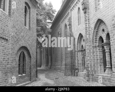 Eine Graustufenaufnahme einer engen Straße, die von alten Gebäuden umgeben ist Stockfoto