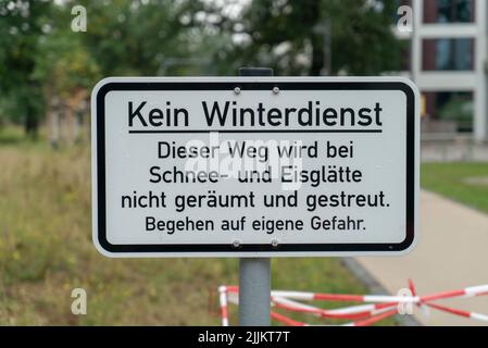 Ein Straßenschild in deutscher Sprache, Übersetzung: 'Kein Winterdienst dieser Weg ist in Schnee und Eis, nicht gerodet und verstreut. Verpflichten Sie sich auf eigenes Risiko.“ Stockfoto
