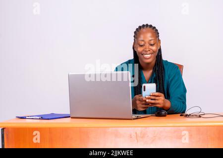Ein Porträt einer jungen afrikanischen schönen Frau, die Smartphone hält, App nutzt oder am Arbeitsplatz chattet Stockfoto