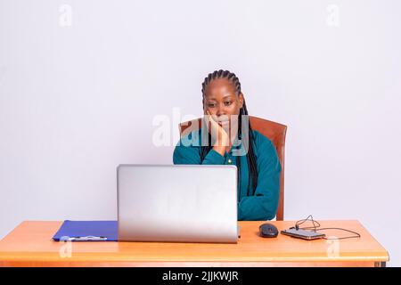Ein Porträt einer afrikanischen Frau, die vor dem Laptop sitzt und dabei an etwas denkt Stockfoto