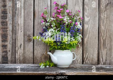 Blumenstrauß mit bunten Wildblumen auf altem Holzhintergrund. Stillleben mit wilden Blumen Stockfoto