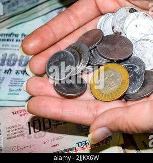 Seltene alte indische Bankrupien-Münzen fallen auf Geldscheine, fallen nach unten indische Rupien-Münzen auf hundert Rupien-Banknoten, indische Währungsmünzen fallen Stockfoto