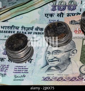 Seltene alte indische Bankrupien-Münzen fallen auf Geldscheine, fallen nach unten indische Rupien-Münzen auf hundert Rupien-Banknoten, indische Währungsmünzen fallen Stockfoto