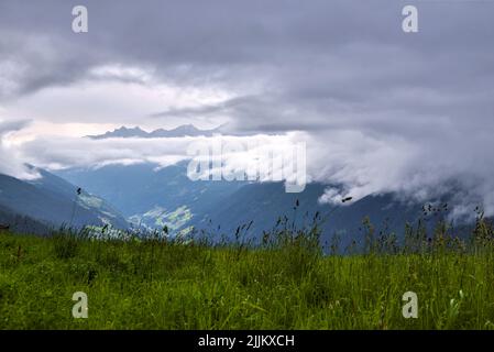 Gewitter Wolken über den Bergen. Grüne Wiesen, verstreute Siedlungen und dunkle Wälder unter beeindruckenden und interessanten Wolken. Stockfoto