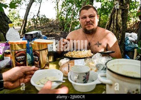 REGION SAPORISCHSCHSCHJA, UKRAINE - 17. JULI 2022 - Militärangehörige der separaten territorialen Verteidigungsbrigade Zaporischschschja speisen an der Front, Saporischschschi Stockfoto